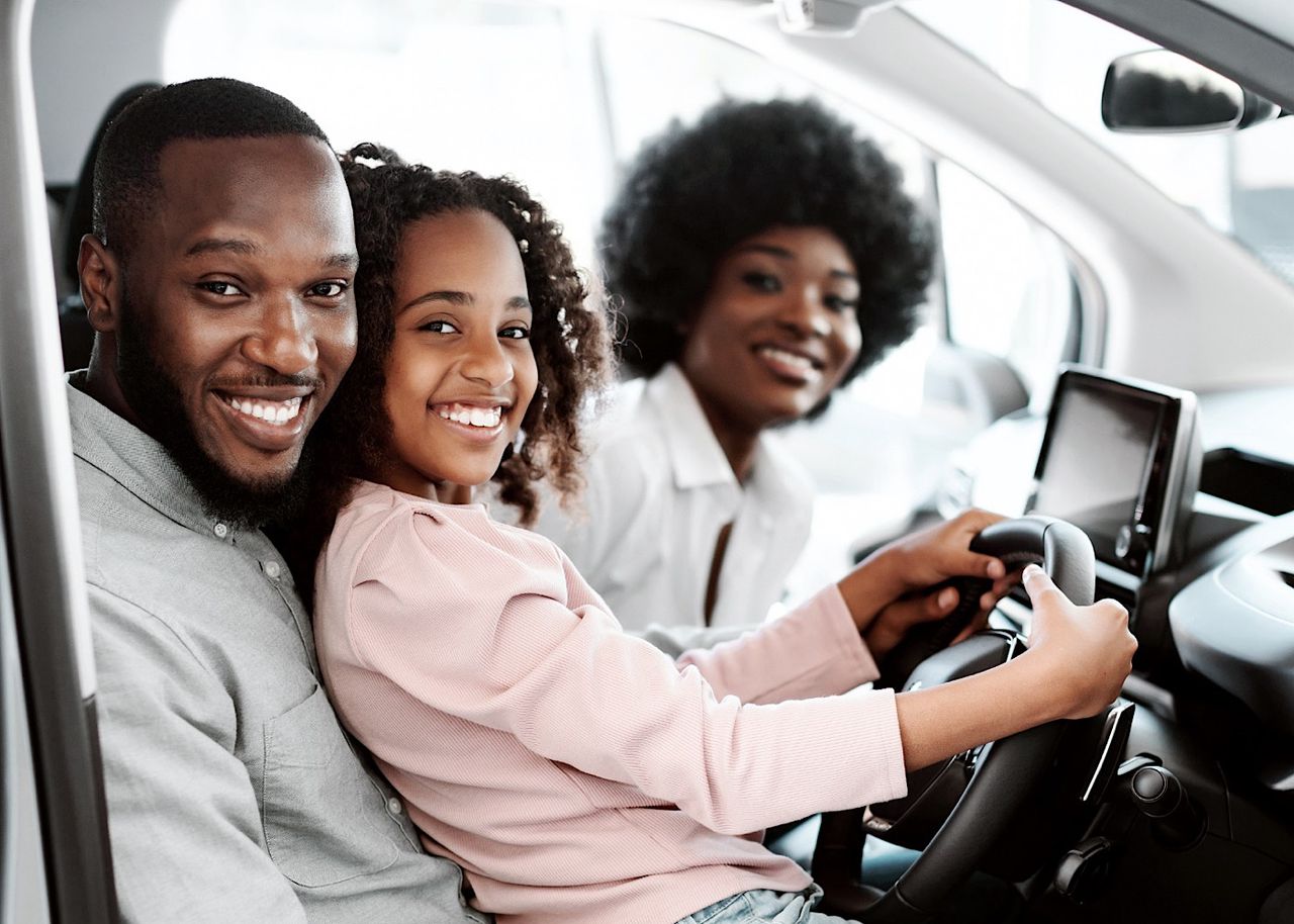 Happy Afro family sitting in new car, going on test drive, buying automobile in dealership store by Prostock-studio