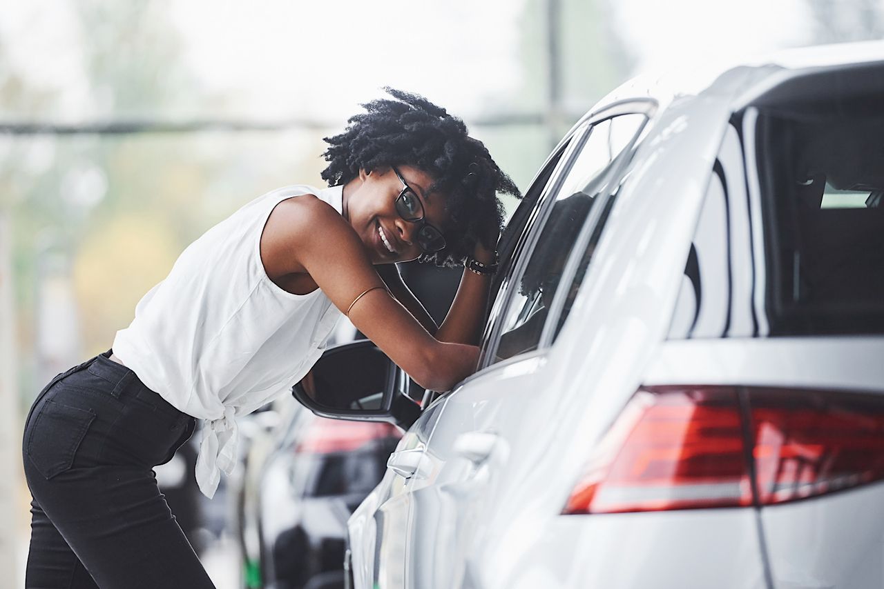 Young african american woman in glasses stands in the car salon near vehicle by mstandret