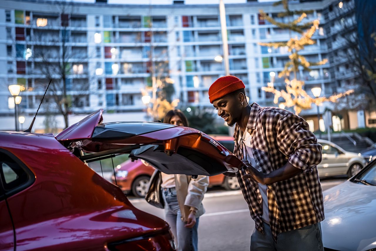 Young couple loading luggage in car trunk by Unai82